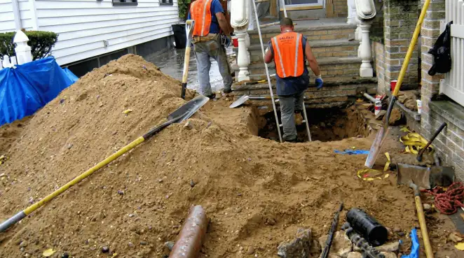 Contractors performing foundation protection and exterior drainage excavation near residential home steps in Overland Park, KS